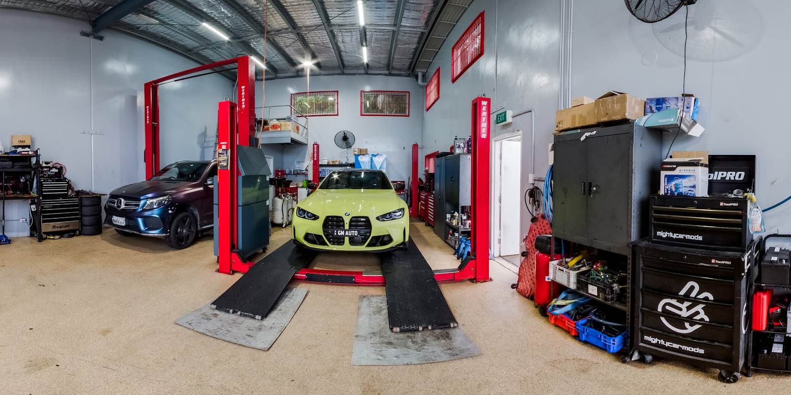 Inside the GM Auto Mechanics workshop in Southport, with two vehicle hoists and a BMW M4 on the ramp